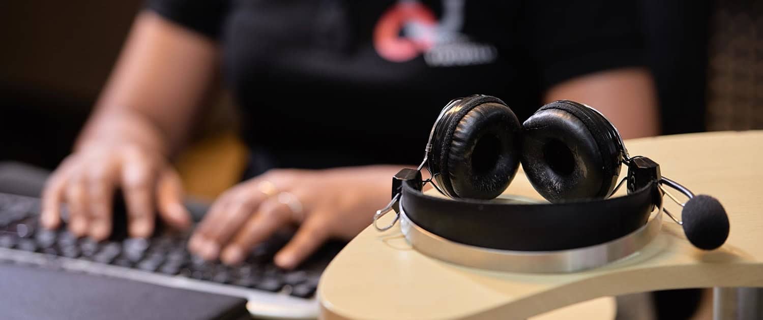 Casque micro de transcription au premier plan, secrétaire virtuelle Assistance Virtuelle au clavier en arrière-plan
