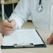 Médecin dictant un compte rendu médical pour frappe sous dictée par une secrétaire médicale à distance