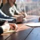 Personnes en réunion professionnelle prenant des notes pour retranscription