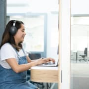 Secrétaire virtuelle concentrée, casque audio, relisant un document de transcription sur son écran d'ordinateur