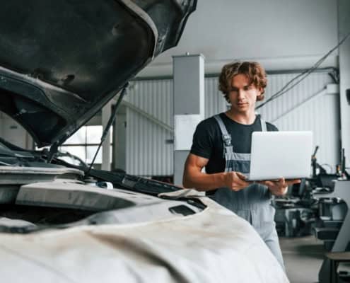 Expert automobile inspectant un véhicule endommagé chez un réparateur